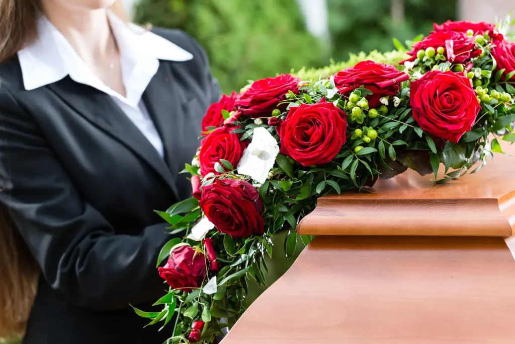 Composition de roses rouges déposée sur un cercueil lors d'obsèques.